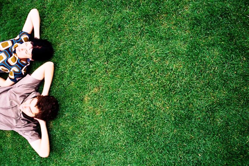 Two people lying on a well kept, green lawn